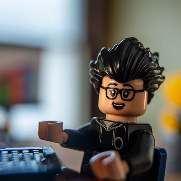 Lego figure at desk working on computer